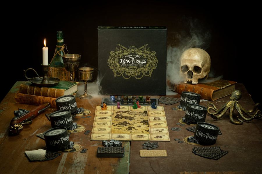 Lying Pirates set up on a wooden table by candlelight, next to a skull and a brass octopus